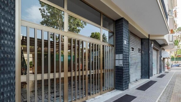 A modern building facade with large glass windows and a metal gate.