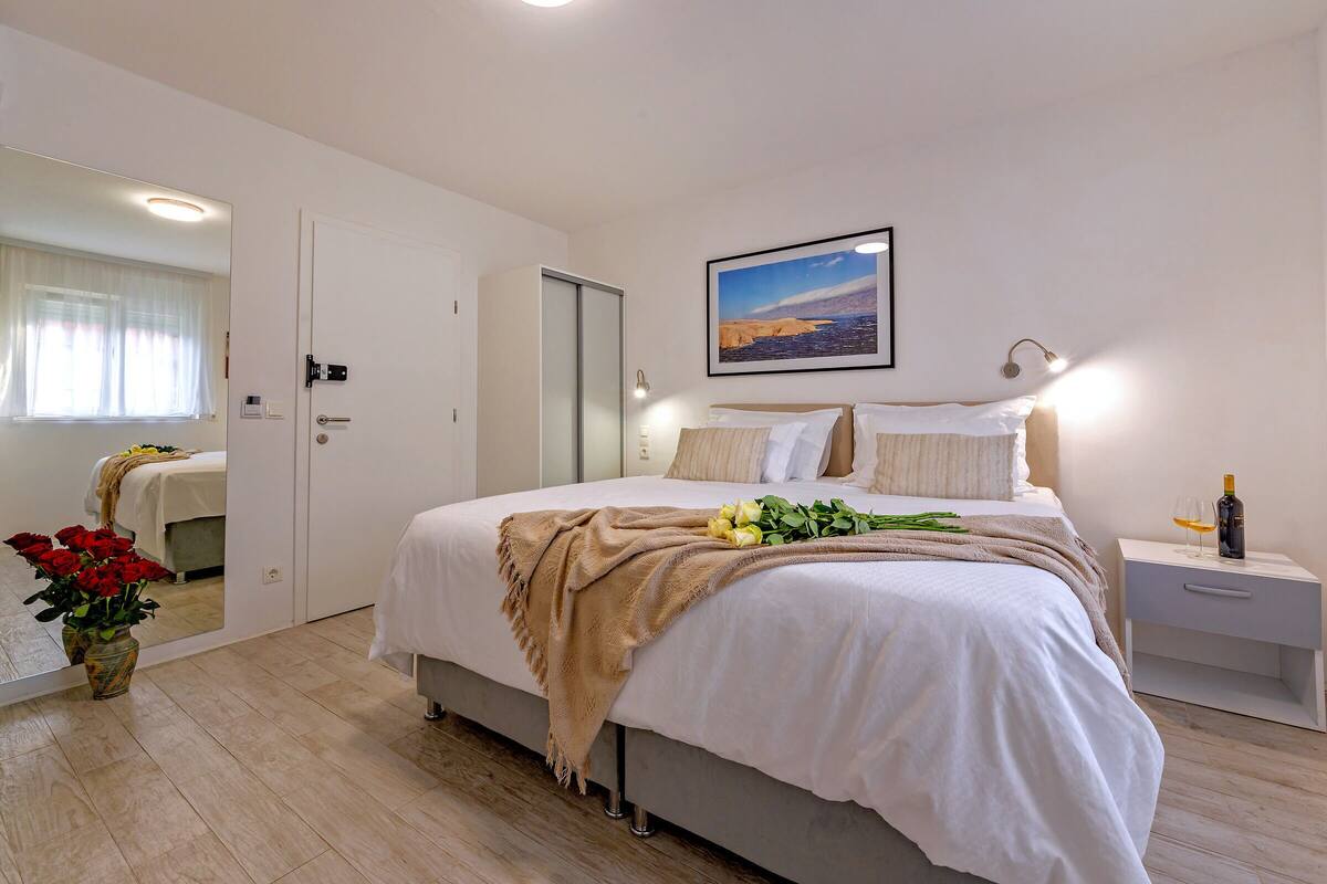 A neatly arranged bedroom with a bed, bedside table, and a nightstand.