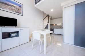A modern kitchen with white cabinets, a dining table with chairs, a flat-screen TV, and a staircase leading to an upper level. - Villa Zvonko (Split)