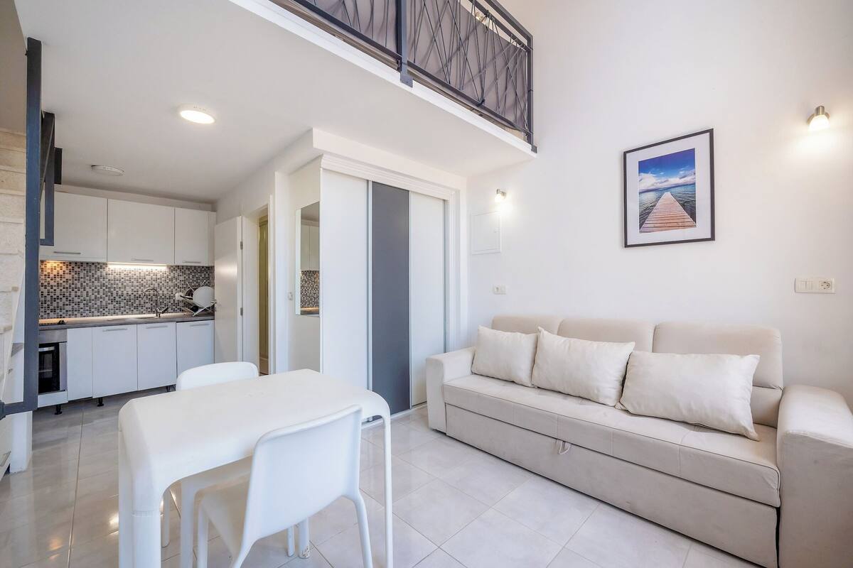A modern living room with a sofa and a dining table.