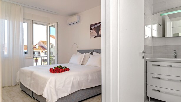 Une chambre avec un lit, une salle de bain avec un lavabo et une vue sur les bâtiments environnants.