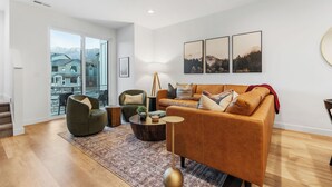 Ein modernes Wohnzimmer mit Sofa, Sessel, Couchtisch und Kunstwerk an der Wand.