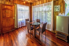 A wooden interior with a dining table, chairs, and a refrigerator. - Violeta Homes Monteverde (Monteverde)