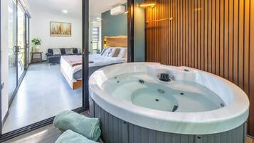 Un dormitorio moderno con una cama grande, un jacuzzi y vistas a un balcón.
