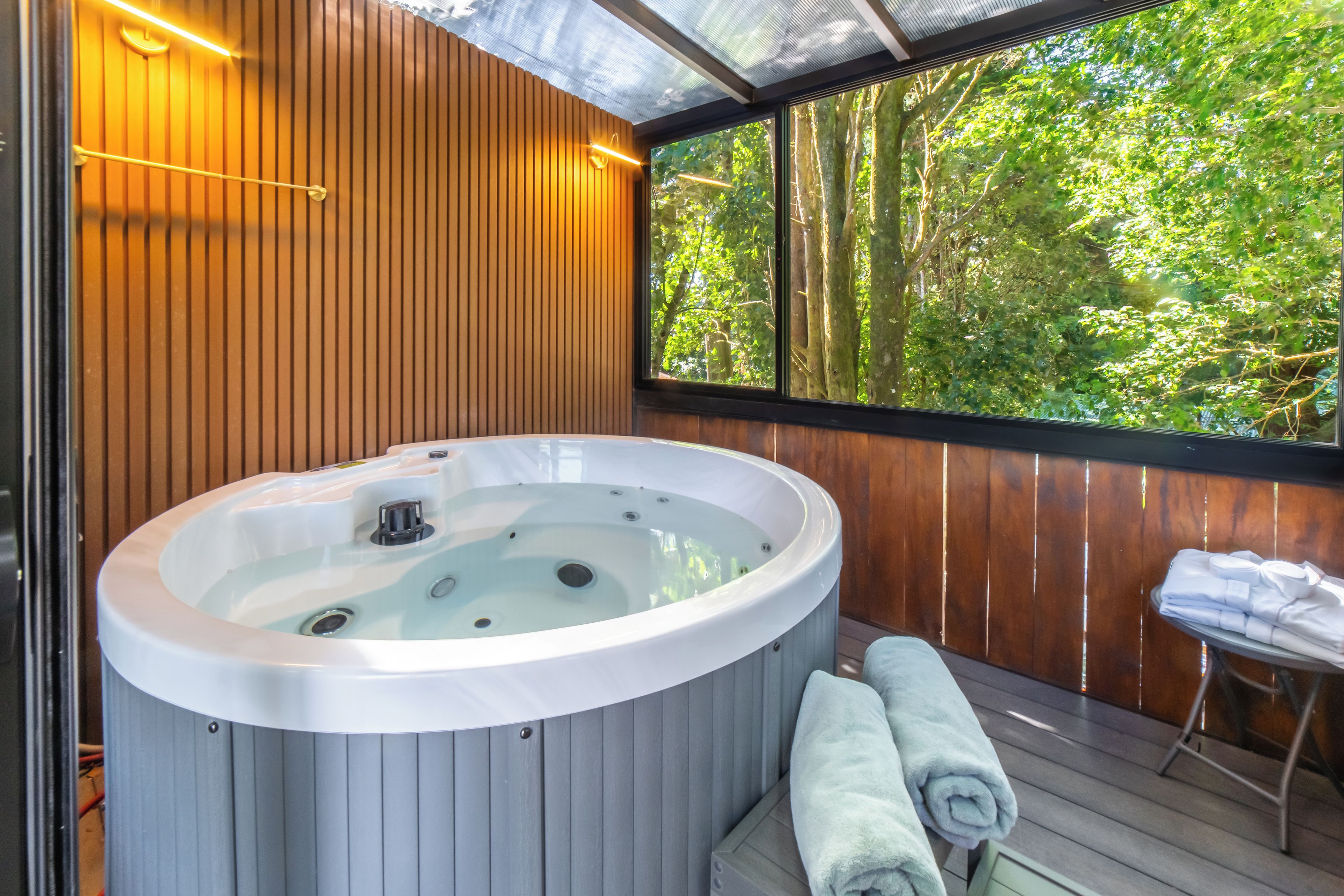 A hot tub with a wooden deck and a view of a forest.