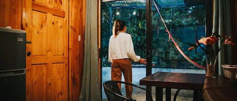 Un intérieur en bois avec une porte-fenêtre coulissante donnant sur un jardin.