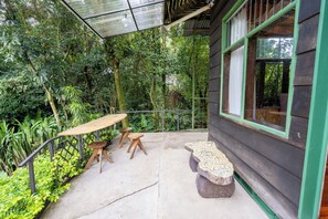 An outdoor patio with a table and chairs, surrounded by lush greenery. - Violeta Homes Monteverde (Monteverde)
