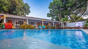A swimming pool with a building in the background, a sign reading "Villa Twelve 27", and a red and yellow structure to the left. - Villa Twelve27 (Sosúa)