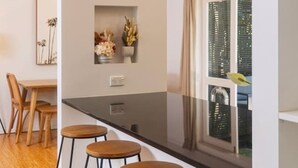 Cocina moderna con una isla central, taburetes de bar, iluminación colgante y vistas a la ciudad a través de amplios ventanales.