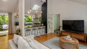 Una sala moderna con un sofá, un televisor y un otoman tejido.