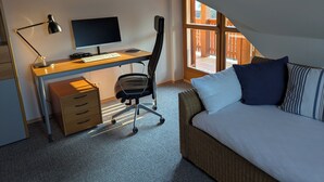 Une chambre à coucher avec un lit, un bureau avec un ordinateur, une chaise et une fenêtre.