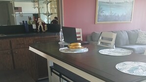 A dining area with a wooden table, two benches, and a glass-top table. There are placemats and a bottle of water on the table. - Naples Florida Paradise - 2 week Min Stays (Naples)