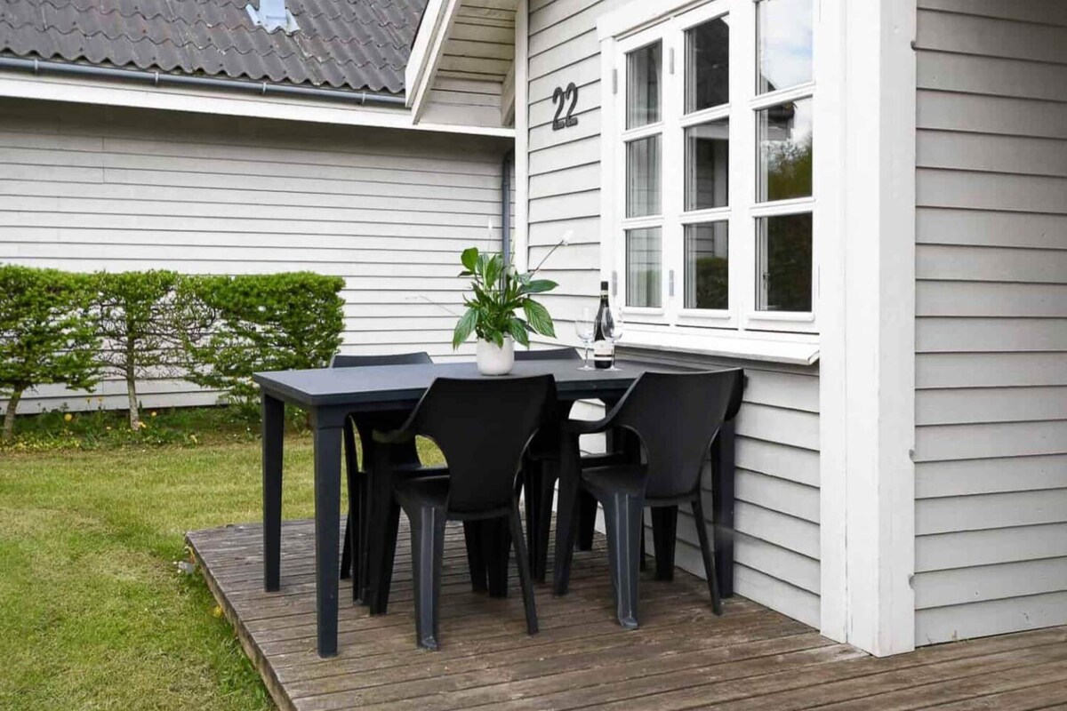 Eine Terrassengruppe im Freien mit Tisch, Stühlen, einem Blumentopf und einer Weinflasche.
