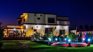 Una casa moderna a due piani con un cortile anteriore ben illuminato e una piccola zona palco.