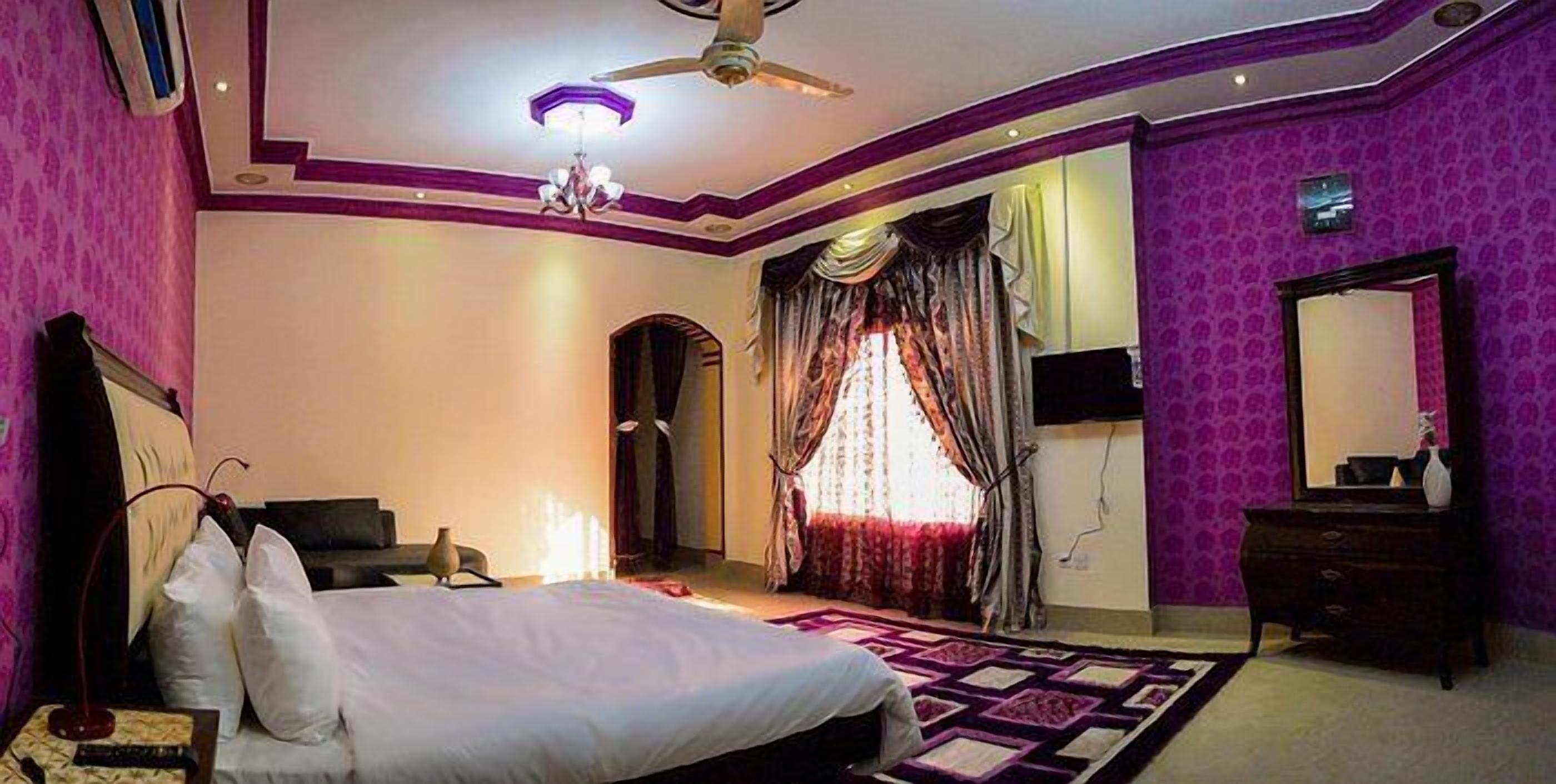 A bedroom with a bed, a dresser, a mirror, and a ceiling fan.