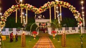 Location per matrimoni all'aperto con percorso rivestito di moquette, archi floreali e luci sospese.