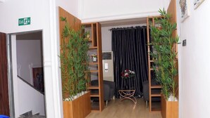 Un couloir avec des étagères en bois, un rideau noir et une petite table ornée de fleurs.