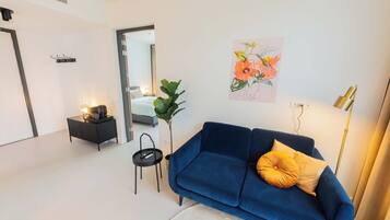 Una sala de estar moderna con un sofá azul, una mesita auxiliar, una planta en maceta y un cuadro en la pared.
