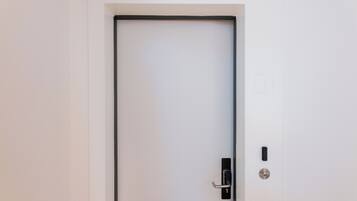 A white door with a black frame, a keyhole, and a modern electronic lock.