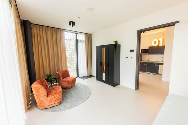 A modern living room with a sofa, a coffee table, and a large window with curtains.