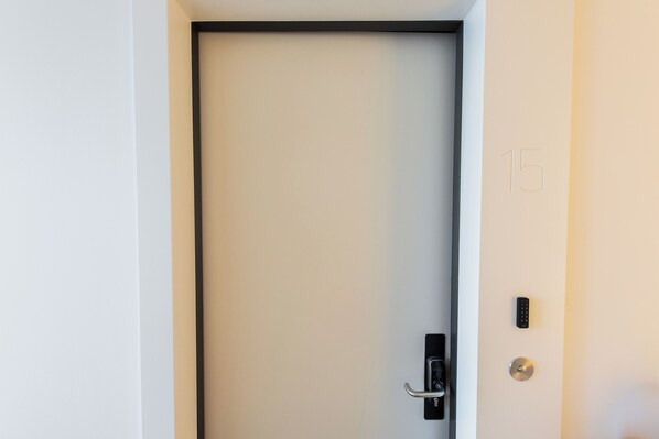 A door with a black frame and a numeric keypad lock. - Alphabet Apartments Brede Hilledijk (Rotterdam)
