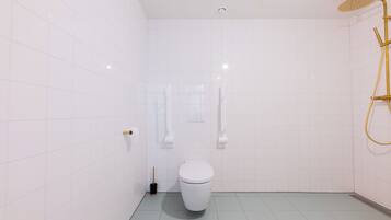 Une salle de bain moderne avec des carreaux blancs, des toilettes blanches, une pomme de douche dorée et un pommeau de douche à main.