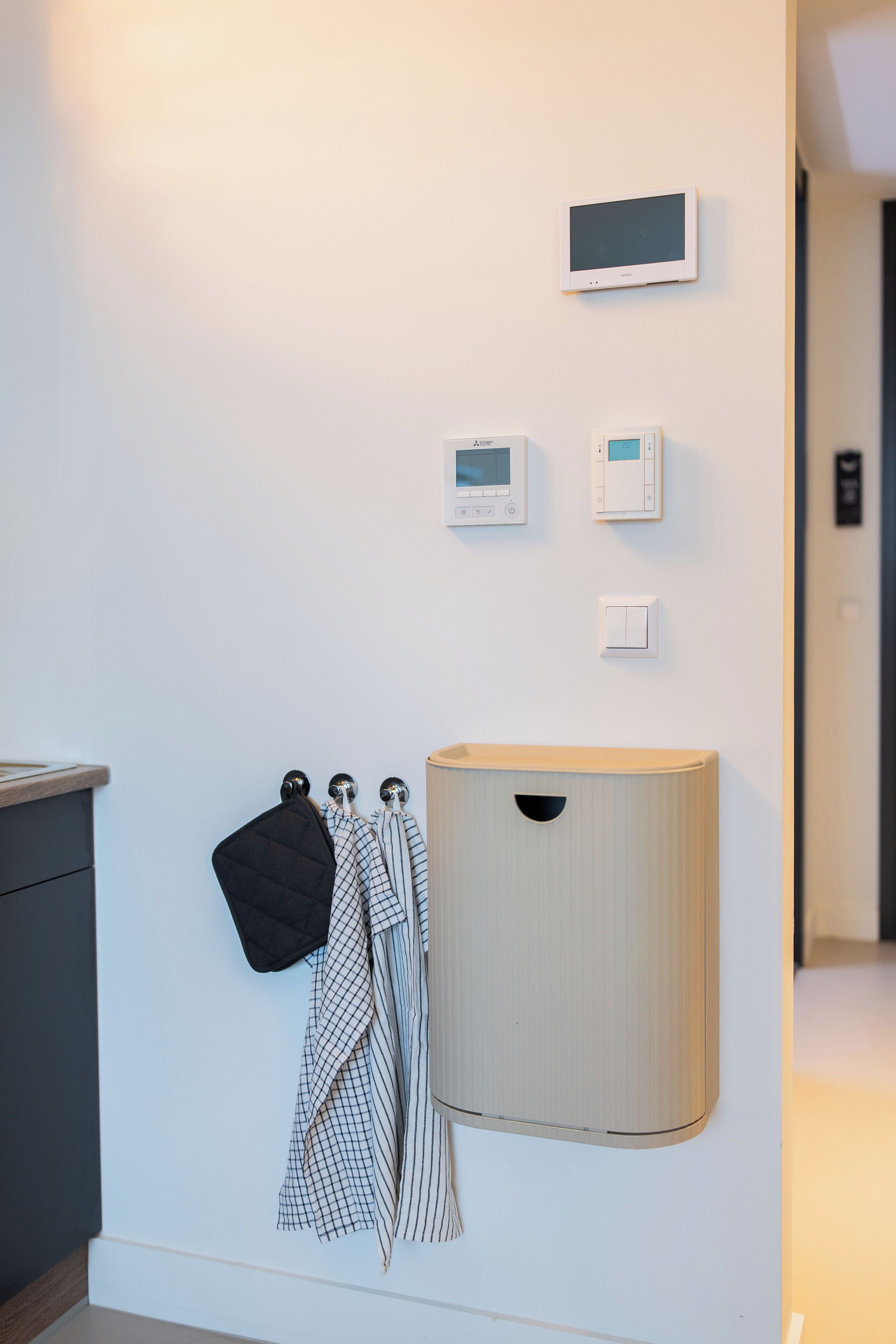 A wall-mounted light fixture, a thermostat, and a small wooden cabinet.
