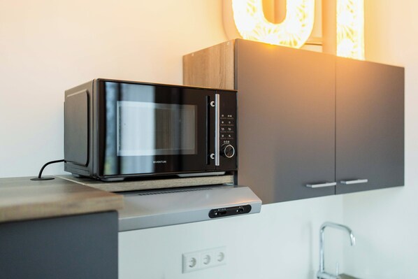 A modern kitchen with a built-in microwave, a wooden cabinet, and a stainless steel sink. - Alphabet Apartments Brede Hilledijk (Rotterdam)