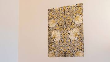 Un comedor con una mesa redonda, dos sillas y una obra de arte floral colgada en la pared.