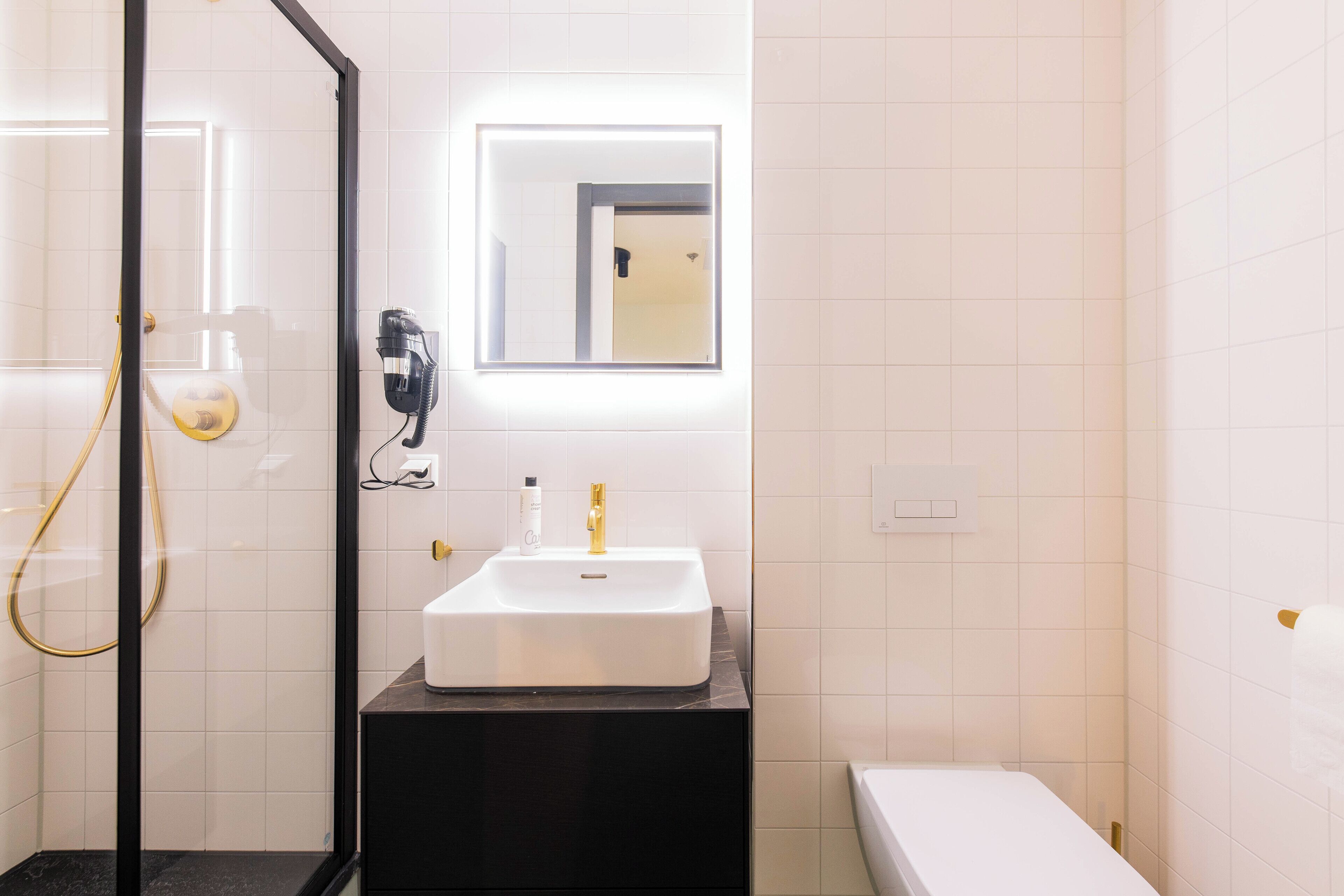 A bathroom with a white sink, a mirror, and a shower.