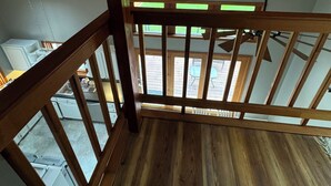 A wooden balcony with a view of a garden and a building in the background. - COZY HILLSIDE HOME WITH A BEAUTIFUL DECK, FIRE PIT, SAUNA & PLENTY OF PARKING (Anchorage)