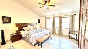 A hotel room with a bed, bedside table, lamp, and a ceiling fan. - Luxurious 2 Bedroom Ajijic Home-bikes-huge Patio-gym-pickleball Court-golf Cart (Chapala)