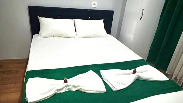 A neatly made bed with white linens and a green bedspread. - Taksim Plaza Suite (Istanbul)
