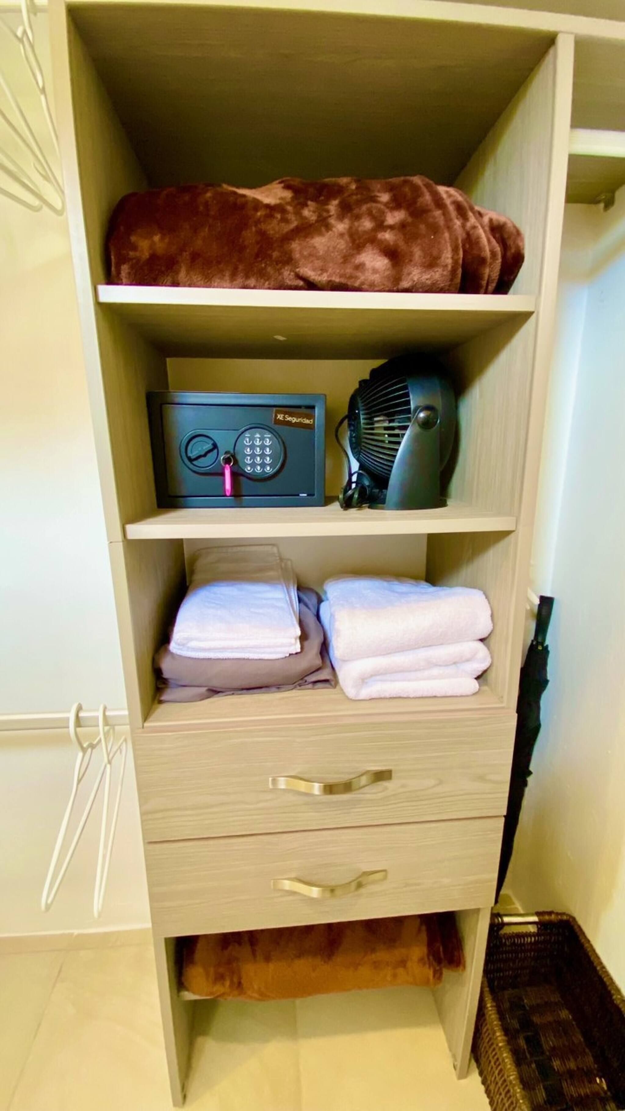 Ein Kleiderschrank mit Radio, Ventilator und gefalteten Handtüchern.