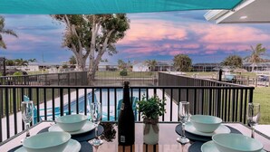 A dining table set with bowls and wine glasses, overlooking a pool and a sunset view. - Newly Remodeled 2/2 Home with Golf Access, Game Room & Salt-Water Heated Pool (Cape Coral)