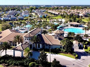 A residential area with a large swimming pool, multiple houses, and palm trees.