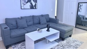 A modern living room with a grey sectional sofa, a white coffee table, and abstract art on the wall. - Cozy Soulard Getaway Near Downtown St. Louis (St. Louis)