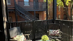 A covered outdoor seating area with a view of a brick building and a staircase. - Cozy Soulard Getaway Near Downtown St. Louis (St. Louis)