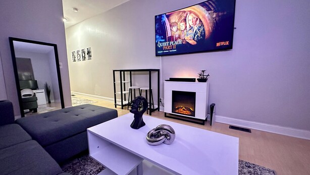 A modern living room with a flat-screen TV, a fireplace, and a sofa. - Cozy Soulard Getaway Near Downtown St. Louis (St. Louis)