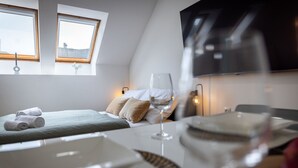 Ein Hotelzimmer mit einem Bett, einem Weinglas und einem gedeckten Esstisch.