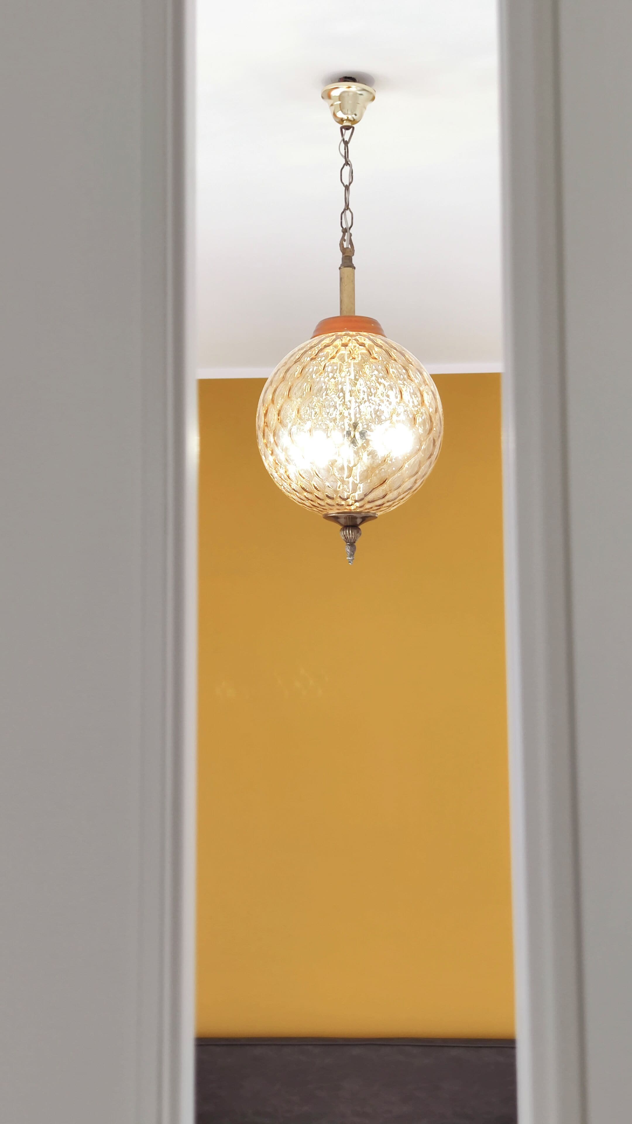 A chandelier with a chain and a spherical glass design hanging from the ceiling.