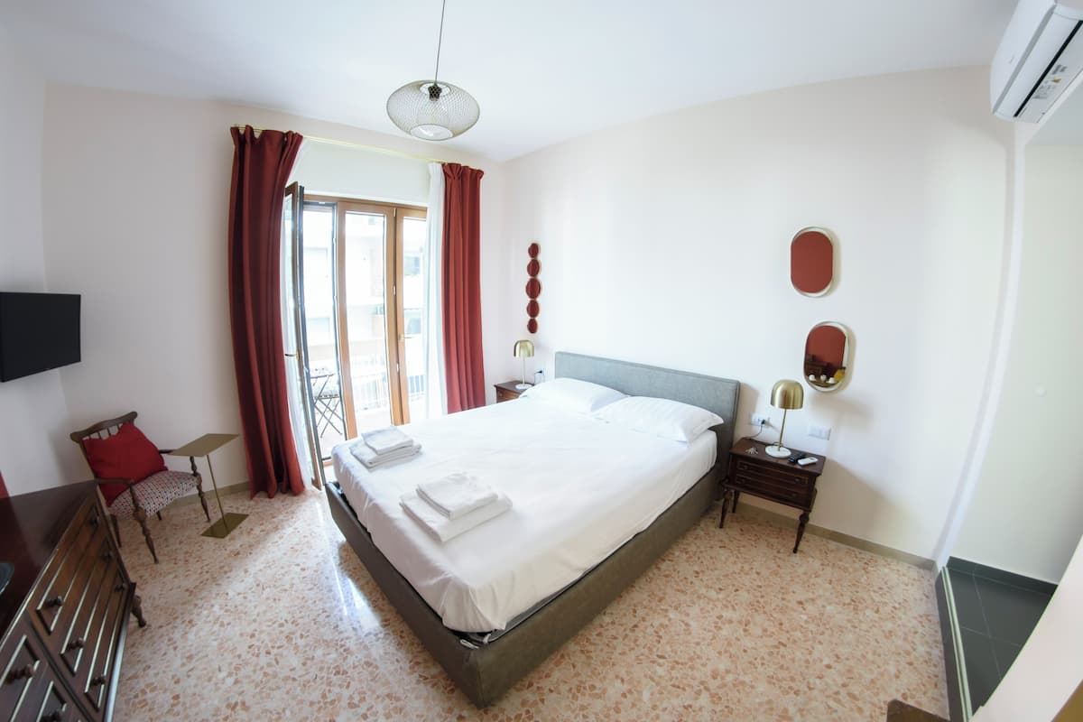 A hotel room with a bed, a desk, a chair, a television, and a window with curtains.