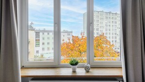 A window with a view of autumn trees and a building across the street. - P&O Apartments Suligowskiego (Warsaw)