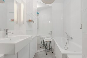 A modern bathroom with a large bathtub, two sinks, and a glass shower enclosure.