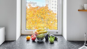 A kitchen with a window view of autumn foliage and buildings. - P&O Apartments Suligowskiego (Warsaw)