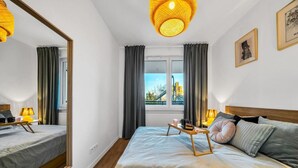 Una habitación de hotel con una cama grande, mesitas de noche, un espejo y una ventana con cortinas.