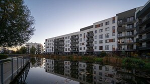 Un moderno edificio de apartamentos con balcones, un canal al frente y un puente.