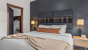 Une chambre d’hôtel comprenant un lit, deux tables de chevet, une armoire et un miroir.