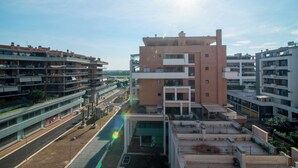 A multi-story residential building with balconies, a central courtyard, and a street view.