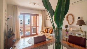 A living room with a sofa, a coffee table, a TV, and a large plant.